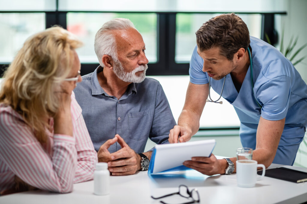 Doctor explaining Medicare insurance plan options to a senior couple during a consultation.